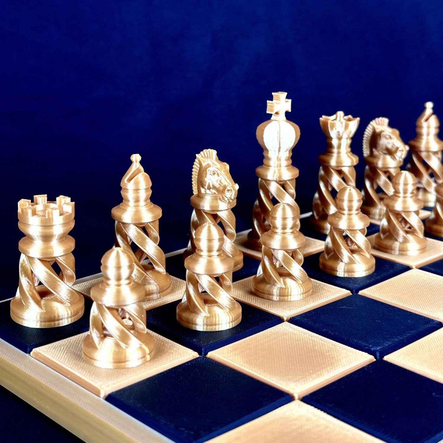 Pièces d’échecs dorées au design moderne posées sur un échiquier, vue de face montrant la silhouette élancée et la finition élégante des pièces Chess Project.