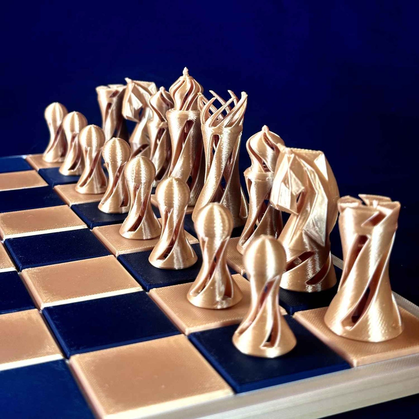 Pièces d’échecs dorées au design twist moderne, vue de face sur un échiquier, montrant les silhouettes originales et l’esthétique contemporaine Chess Project.